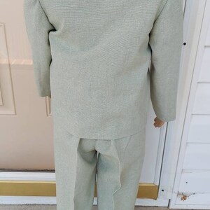 May include: A light green suit with a white collar. The suit is made of a textured fabric and has a classic style.