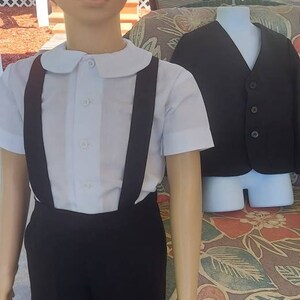 May include: A white collared shirt with black suspenders and black shorts. A black vest is on a mannequin in the background.
