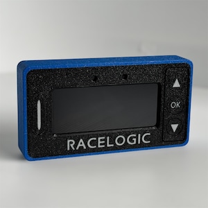 May include: A rectangular Racelogic electronic display device featuring a blue outer frame and a black textured front panel. The device includes a central screen, a vertical white indicator light, and three buttons labelled with up, down, and OK symbols.