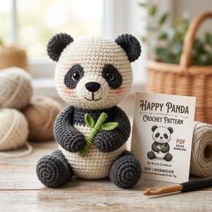 Könnte beinhalten: Ein gehäkeltes Panda-Spielzeug mit cremefarbenem Kopf und Körper, dunkelgrauen Ohren, Gliedmaßen und Augenpartien, das einen kleinen grünen Bambuszweig hält. Daneben steht eine Karte mit der Aufschrift Happy Panda Crochet Pattern und PDF-Symbol.