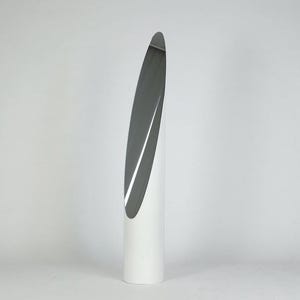 May include: A tall, cylindrical floor mirror featuring a smooth white base and a long, narrow, vertical reflective glass panel that curves slightly along the front surface, creating a sleek, elongated, and modern appearance for any interior space.