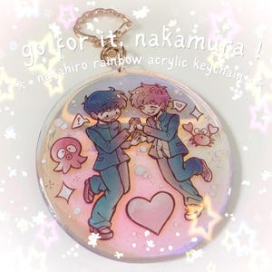 Puede incluir: Un llavero redondo de acrílico arcoíris con una ilustración de dos personajes con uniforme escolar tomados de la mano, rodeados por un corazón rosa, un pulpo pequeño y un cangrejo. El texto dice go for it, nakamura! nakahiro rainbow acrylic keychain.