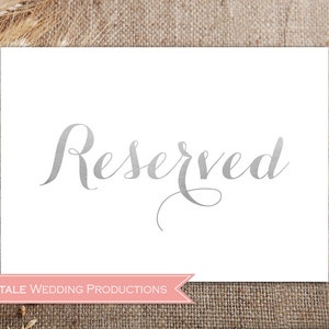May include: A white card with the word "Reserved" written in silver script. The card is on a brown burlap background. The text "Fairytale Wedding Productions" is printed in pink at the bottom of the card.