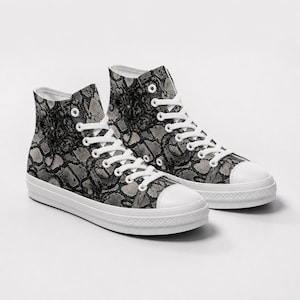May include: A pair of high-top sneakers featuring a black and gray snakeskin pattern across the canvas upper. The shoes include white laces, white metal eyelets, a white rubber toe cap, and a thick white rubber sole with a textured front bumper.