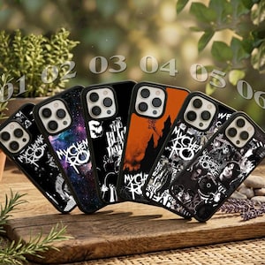 Pode incluir: Seis capas para smartphone dispostas em fila, cada uma com designs distintos, incluindo padrões de galáxias, silhuetas de castelos e gráficos em estilo colagem com o texto My Chemical Romance impresso em várias das capas pretas e laranjas.
