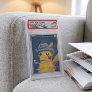 Könnte beinhalten: Eine bewertete 2023 Pokemon SVP EN Pikachu with Grey Felt Hat Sammelkarte in einer durchsichtigen Kunststoffhülle. Die Karte zeigt ein gelbes Pikachu mit einem blauen Hut vor einem blauen, wirbelnden Hintergrund mit dem Text Pika-Portrait und Pokemon x Van Gogh.