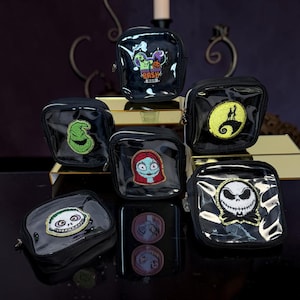 May include: A collection of six square, black, transparent vinyl pouches featuring embroidered patches of characters from The Nightmare Before Christmas, including Jack Skellington, Sally, Oogie Boogie, and a Oogie Boogie Bash logo patch.