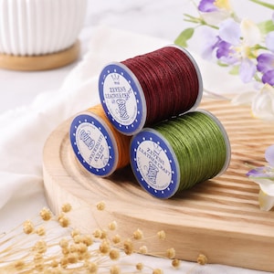 May include: Three spools of Zevens Leather Craft polyester waxed thread in dark red, orange, and olive green. Each spool features a circular white label with blue text and a crown icon, indicating the brand name and product type clearly.