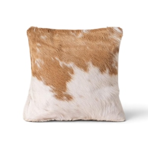 May include: A square throw pillow covered in genuine cowhide featuring a natural pattern of light tan and white fur. The texture is short and dense, displaying organic color variations across the entire surface of the cushion cover.
