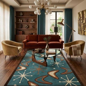 May include: A rectangular area rug featuring a teal background with a repeating pattern of brown boomerangs and white starburst shapes. The rug has a dark brown border and is positioned in a living room with a rust-coloured sofa and two gold chairs.