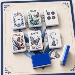 May include: A set of rectangular Mahjong tiles featuring white surfaces with blue, red, and green floral and butterfly illustrations. The tiles display text including 1, BAM, 4, CRAK, and JOKER, arranged on a cream-colored board with blue borders.