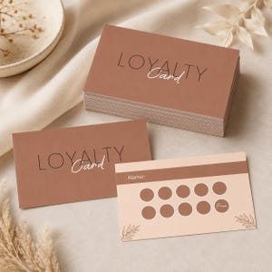 May include: A stack of rectangular loyalty cards and two individual cards in a terracotta brown color. The cards feature the text "LOYALTY Card" in a thin black and white font. One card shows a name field and ten circular spots for stamps.