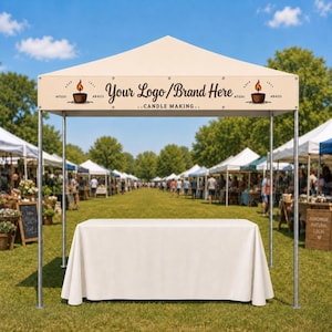 May include: A beige pop-up canopy tent with a white tablecloth-covered table underneath. The canopy valance features the text "Your Logo/Brand Here", "..CANDLE MAKING..", and "DEAR LEST #FEDO #B4513" with illustrations of a lit candle on both sides.