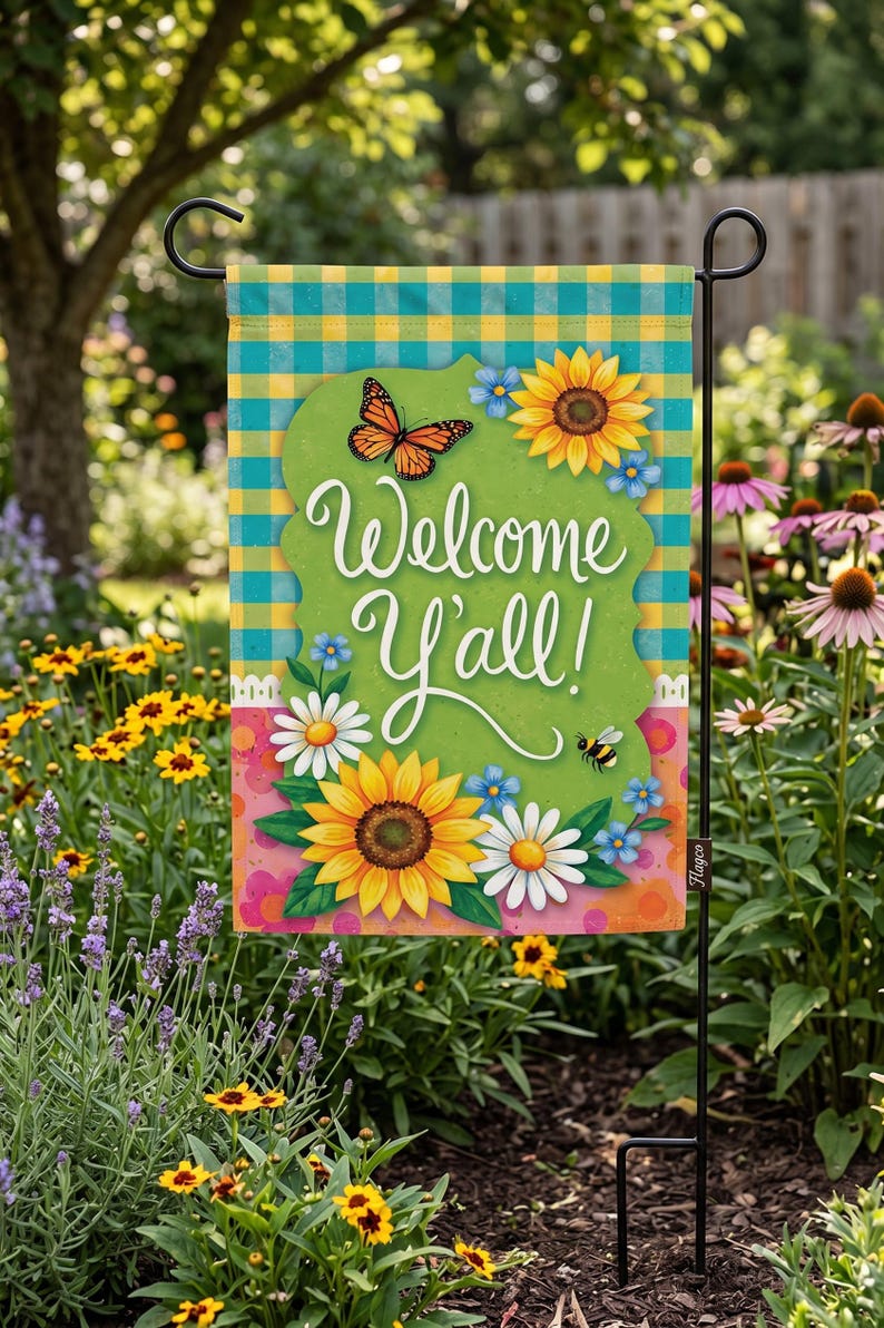 A colorful garden sign with a welcoming message, surrounded by flowers and greenery.