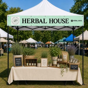 May include: A white pop-up canopy tent with a light green banner reading HERBAL HOUSE. A table displays potted herbs, brown glass dropper bottles, a bag labeled HERBAL TEA, and small chalkboard signs with text including NATURE HEALS ALWAYS.