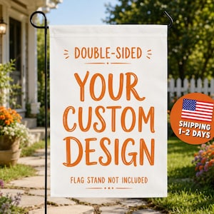 May include: A white rectangular garden flag hanging on a black metal stand. The flag features orange text that reads DOUBLE-SIDED, YOUR CUSTOM DESIGN, and FLAG STAND NOT INCLUDED, with decorative lines and dots surrounding the text elements.