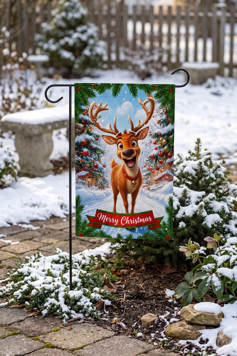 A festive Christmas-themed garden flag featuring a cartoon reindeer standing in a snowy landscape, with a "Merry Christmas" banner below.