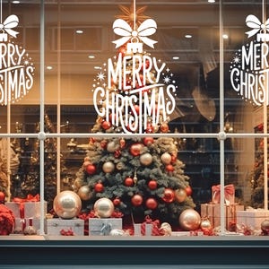 May include: Three white vinyl window decals featuring a stylized Christmas ornament shape with a bow on top and the text Merry Christmas in a decorative script font. The decals are applied to a glass window displaying holiday decorations.