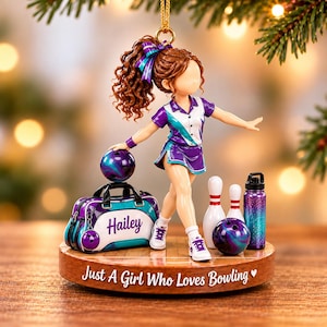 May include: A bowling-themed ornament featuring a figure with brown curly hair wearing a purple and white shirt and skirt. The figure stands next to a bowling bag labeled Hailey, two white pins, a bowling ball, and a water bottle. The base reads Just A Girl Who Loves Bowling.
