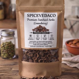 Może przedstawiać: Brązowa torebka z papieru typu kraft zawierająca suszone kawałki agrestu amla. Etykieta zawiera napis SPICEVEDACO Premium Sundried Amla (Gooseberry), Premium Quality, Rich in Nutrients, High in Fiber, Natural & Pure, Energy Booster, Masa netto 200g.