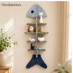 May include: A wall-mounted fish skeleton shelf with a distressed light blue head and dark blue tail. The wooden structure features five horizontal shelves holding a white cat figurine, a wooden tree, a succulent, and two small whale figures.