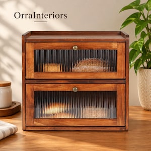 May include: A two-tier wooden storage cabinet with a dark brown finish, featuring two drop-down doors with fluted glass panels and small round brass-toned knobs. The text OrraInteriors is visible in the upper left corner of the image.