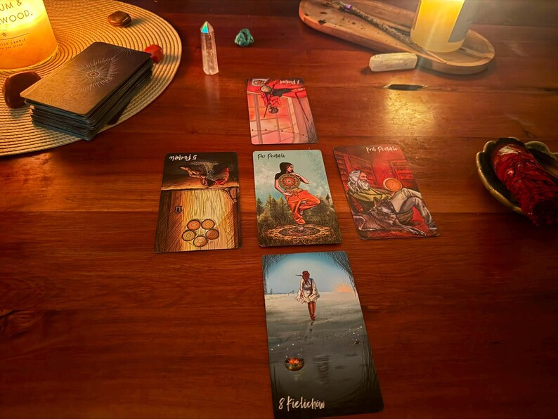 May include: A tarot card spread arranged in a cross pattern on a wooden surface, featuring five cards including the Eight of Pentacles, Five of Pentacles, and Page of Pentacles. The cards display colorful illustrations, and a deck of cards sits nearby.