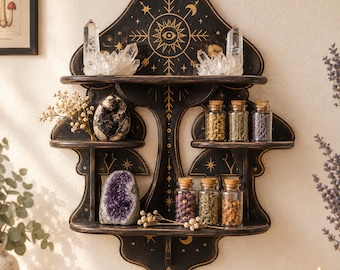 May include: A black wooden wall shelf shaped like a mushroom, featuring gold celestial symbols including an eye, stars, and moons. The shelf holds clear quartz clusters, a dark geode, a purple amethyst, and six small glass jars with cork lids.