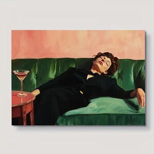 May include: A painting depicting a person with dark hair resting on a tufted emerald green sofa against a soft pink wall. A small round red side table stands to the left, holding a stemmed glass filled with a light-coloured liquid.
