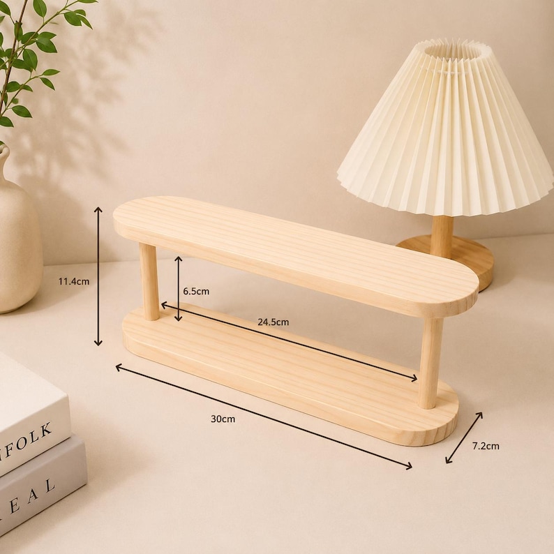 May include: A light-colored wooden two-tier display shelf with rounded ends and four cylindrical supports. The shelf measures 30 cm in total length, 7.2 cm in width, and 11.4 cm in total height, with a 6.5 cm clearance between the two tiers.