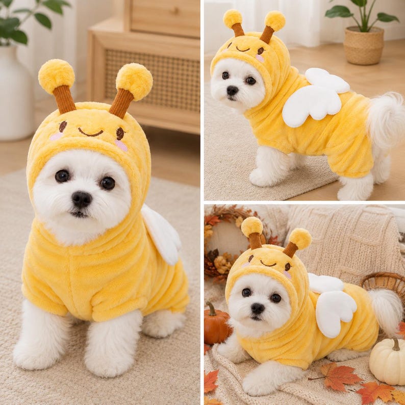 May include: A plush yellow bee costume for a small dog, featuring a hood with two brown antennae, a smiling face embroidered on the front, and white fabric wings attached to the back. The soft, fuzzy garment covers the torso and head.
