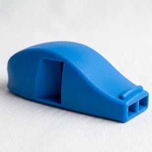 May include: A solid blue whistle with a smooth, curved top surface and a rectangular sound chamber opening on the side. The front end features two distinct rectangular air outlets, and the overall design is sleek, compact, and uniform in color.