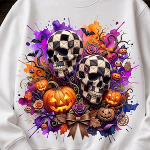Peut inclure: Un sweat-shirt blanc à manches longues avec une impression graphique vibrante représentant deux crânes à damier, plusieurs citrouilles d'Halloween lumineuses, des éclaboussures d'aquarelle violettes et orange, des branches et des nœuds.