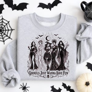 A heather gray crewneck sweatshirt displayed flat with a black gothic witches graphic surrounded by bats, a pumpkin, and a spider.