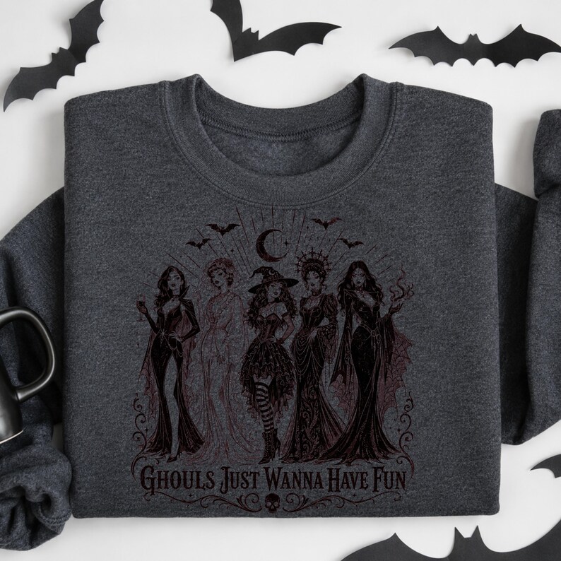 A dark charcoal gray crewneck sweatshirt featuring a dark red or black witch illustration with the text Ghouls Just Wanna Have Fun.