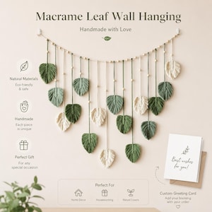 May include: A macrame wall hanging featuring a horizontal cord adorned with small wooden beads and multiple dangling leaf-shaped fiber elements in alternating shades of sage green and cream, accompanied by a white greeting card with text.