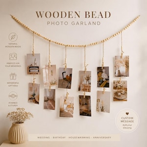 May include: A wooden bead photo garland featuring a long string of light-colored beads with multiple hanging vertical strands. Each strand includes small wooden clips to hold rectangular photographs. The text reads WOODEN BEAD PHOTO GARLAND.