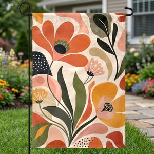 May include: A rectangular garden flag featuring a stylized floral pattern with large orange, yellow, and pink blossoms. The design includes dark green leaves, black dotted accents, and organic shapes on a cream background, suspended from a metal stand.
