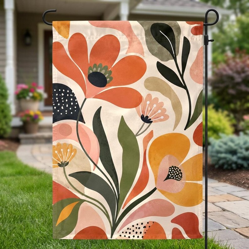 May include: A rectangular garden flag featuring a botanical pattern with large orange and yellow flowers, dark green leaves, and abstract shapes in shades of pink and cream. The design includes small black dots and organic flowing lines throughout.