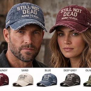 May include: A collection of distressed baseball caps in burgundy, sand, blue, deep grey, and olive green. Each cap features the embroidered text STILL NOT DEAD and HARD TO KILL on the front, with the words NO QUIT printed on the side panel.