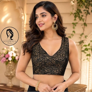 Könnte beinhalten: Eine ärmellose schwarze Bluse mit V-Ausschnitt und einem komplizierten goldenen Blumenmuster auf dem gesamten Stoff. Das Kleidungsstück wird mit goldenen Creolen und einem goldenen Perlenarmband kombiniert. Ein kreisförmiges Logo mit dem Text ROOPKALA Fashion ist sichtbar.
