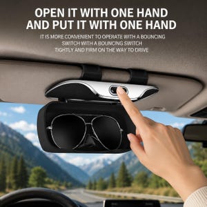 Op de afbeelding: Een zwarte zonnebrilhouder voor de zonneklep met een zilveren rand en een drukknopmechanisme. De tekst luidt: OPEN IT WITH ONE HAND AND PUT IT WITH ONE HAND. IT IS MORE CONVENIENT TO OPERATE WITH A BOUNCING SWITCH TIGHTLY AND FIRM.