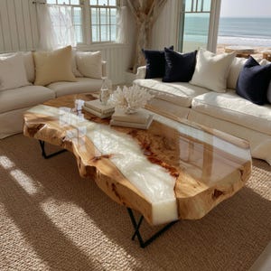May include: A live edge coffee table featuring a natural wood slab with a central white resin river inlay, supported by black metal legs. The table surface is polished and smooth, showcasing the wood grain and the opaque white resin center.