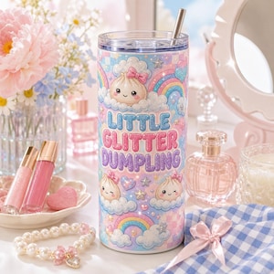 Peut inclure: Un gobelet cylindrique avec un couvercle transparent et une paille en métal, orné d'un motif pastel de nuages, d'arcs-en-ciel, d'étoiles et de raviolis dessinés avec des nœuds roses. Le texte "LITTLE GLITTER DUMPLING" est écrit en grosses lettres.
