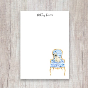 May include: White notepad with the text "Ashley Davis" at the top. A watercolor illustration of a pug sitting in a blue floral armchair is on the bottom right corner. The chair has gold trim.