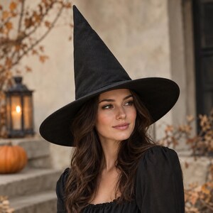 May include: A tall, pointed black witch hat with a wide, structured brim. The hat is crafted from a solid black fabric and features a classic conical crown that tapers to a point, providing a distinct silhouette for costume wear.