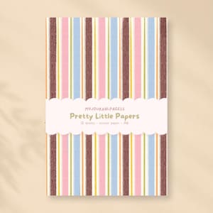 Può includere: Una confezione rettangolare di carta adesiva con un motivo a righe verticali marroni, rosa, azzurre, gialle e verdi. Una fascia di carta bianca smerlata al centro riporta il testo MYJOURNALPAGESS Pretty Little Papers 12 sheets - sticker paper - A6.