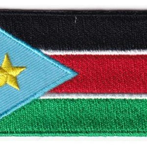 May include: A rectangular embroidered patch featuring the flag of South Sudan. The design includes a light blue triangle on the left with a centered yellow star, followed by horizontal stripes of black, red, and green separated by white lines.