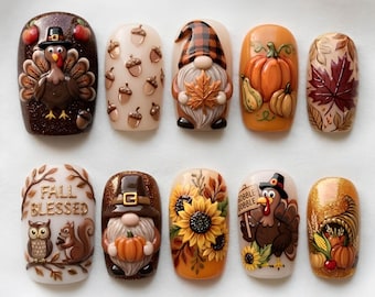 May include: A set of ten press-on nails featuring 3D autumn designs including a turkey, acorns, a gnome, pumpkins, maple leaves, sunflowers, an owl, a squirrel, and a cornucopia. One nail displays the text FALL BLESSED and another GOBBLE GOBBLE.