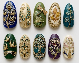 May include: A set of ten oval-shaped press-on nails featuring intricate gold-toned raised designs. Patterns include a peacock feather, floral vines with pearls, a dragonfly on a lily pad, oak leaves, ivy, swallows, geometric lattice, a tree, a rose, and lilies.